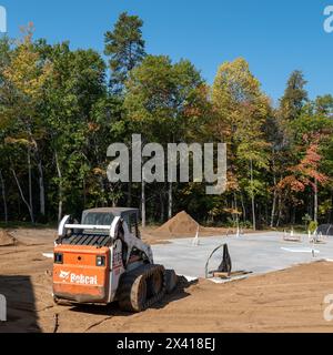 CROW WING CO, MN - 6 giugno 2021: Un caricatore frontale compatto Bobcat S185, bianco e arancione, con cingoli minipala gommata SSL, si trova sullo sporco vicino al calcestruzzo versato sla Foto Stock