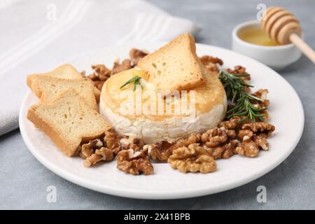 Gustoso camembert al forno, crostini, noci e rosmarino sul tavolo grigio, primo piano Foto Stock