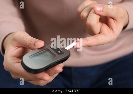 Test del diabete. Uomo che controlla il livello di zucchero nel sangue con il glucometro, primo piano Foto Stock