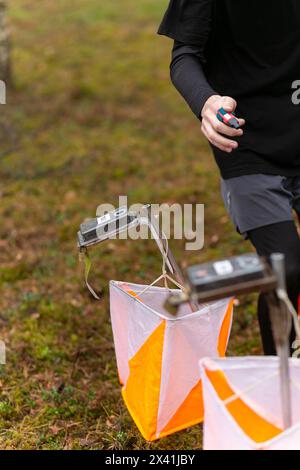 Un ragazzo che pugni al punto di controllo dell'orientamento da vicino. Ragazzo nella foresta che controlla un punto di controllo. Messa a fuoco selettiva Foto Stock