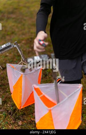 Un ragazzo che pugni al punto di controllo dell'orientamento da vicino. Ragazzo nella foresta che controlla un punto di controllo. Messa a fuoco selettiva Foto Stock