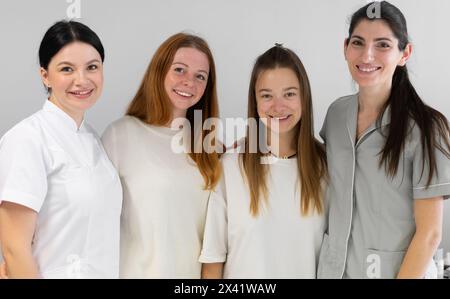 Ritratto di gruppo di cosmetologi in uniforme in piedi insieme e guardando la fotocamera. Dermatologi femminili che sorridono alla macchina fotografica nella clinica di bellezza. Foto Stock