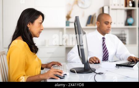 Donna d'affari ispanica che lavora con un computer in ufficio Foto Stock