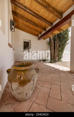 Un patio con tetto in legno e pavimenti in terracotta e vasi decorativi in argilla Foto Stock