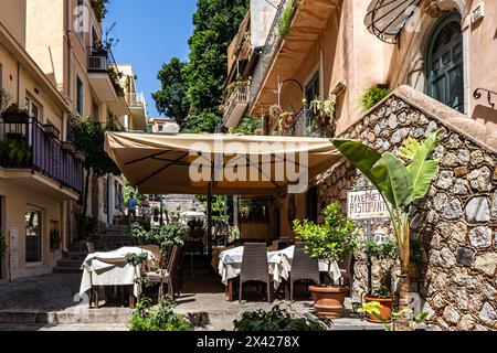 Roma, Italia - 16 luglio 2023: Vista di vecchi edifici in pietra con piante in vaso sui balconi e posti a sedere all'aperto di un ristorante in una giornata estiva a Roma, i Foto Stock