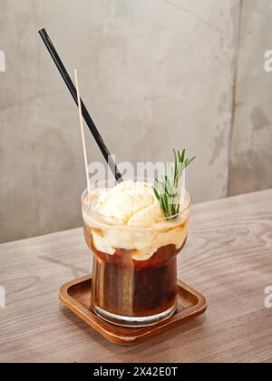 Un bicchiere di caffè con gelato alla vaniglia su un tavolo di legno. Foto Stock