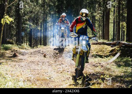 REPUBBLICA DI CARELIA, RUSSIA - CIRCA GIUGNO 2022: Torneo fuoristrada Ladoga Trophy 2022 in Carelia. Un pilota motociclistico su moto sportive salta su una collina nella foresta in una gara di motocross Foto Stock