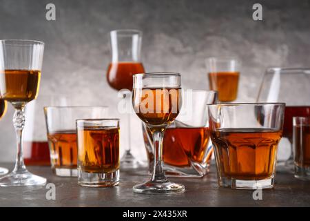 Diversi deliziosi liquori in bicchieri sul tavolo grigio Foto Stock