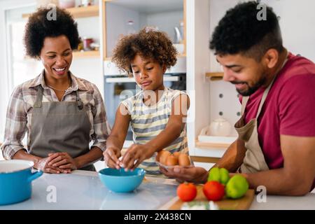 Felice famiglia afro-americana che prepara cibo sano in cucina, divertendosi insieme nel fine settimana Foto Stock