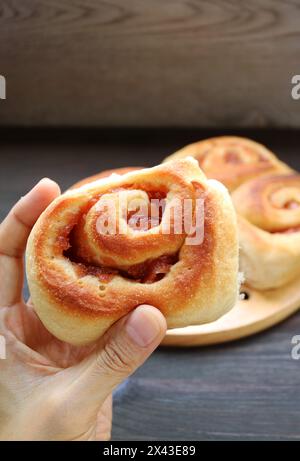 Primo piano di appetitoso rotolo sano di cannella di mela a basso contenuto di zucchero in mano Foto Stock