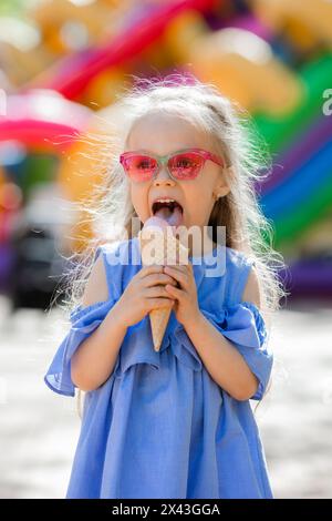 la bambina felice mangia il gelato nel parco in estate. Foto di alta qualità Foto Stock