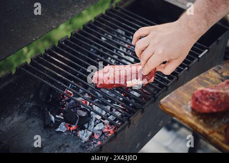 L'uomo irriconoscibile ha messo la bistecca cruda sulla griglia Foto Stock