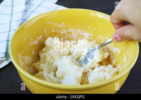 Mescolare a mano il composto in un recipiente con un cucchiaio per cuocere il pane brasiliano al formaggio Foto Stock