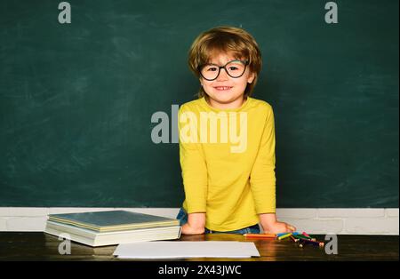 Giornata degli insegnanti. La scuola o l'asilo imparano. Concetto di educazione scientifica. Bambino allegro sorridente alla lavagna. Foto Stock