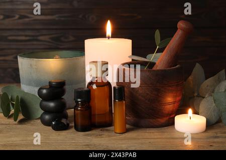 Aromaterapia. Candele profumate, bottiglie, rami di eucalipto e Malta su tavola di legno Foto Stock