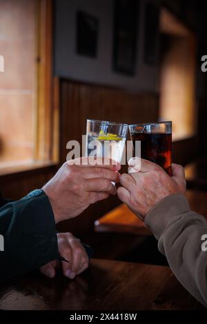 Due bicchieri di drink di due amici al bar che brindano su un tavolo di legno Foto Stock