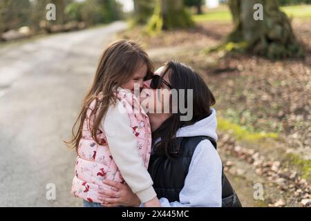 Madre e figlia si baciano sulla strada in campagna. Messa a fuoco selettiva. Foto Stock