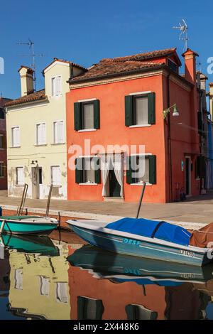 Barche ormeggiate sul canale fiancheggiate da case in stucco rosse e gialle, Isola di Burano, Laguna Veneta, Venezia, Veneto, Italia Foto Stock