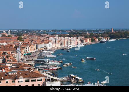 Taxi d'acqua e vaporetti lungo la passeggiata di Riva degli Schiavoni, oltre a edifici residenziali e palazzi in stile architettonico rinascimentale Foto Stock