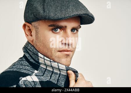 Uomo alla moda con cappello in tweed su morbido sfondo bianco e spazio per le copie. Ispirazione in stile Peaky Blinders Foto Stock