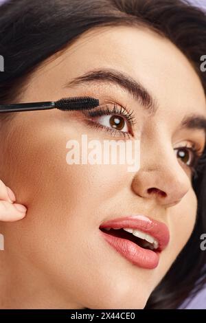 Una donna di bellezza naturale applica il mascara alle sue ciglia. Foto Stock