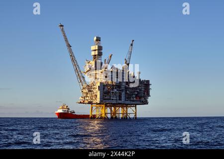 Vista panoramica ravvicinata della piattaforma offshore per giacimenti di petrolio e gas, durante le operazioni di carico con la nave di rifornimento, durante una splendida giornata in mare. Foto Stock