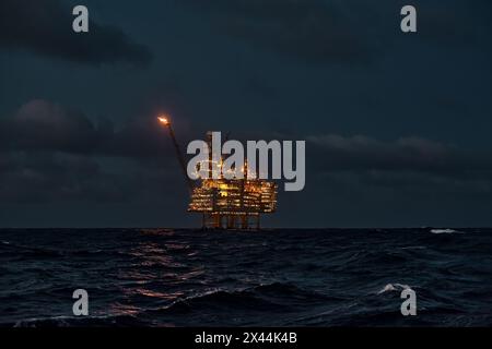 Vista panoramica del giacimento di petrolio offshore nel mare di notte, con piattaforma di perforazione di petrolio e gas all'orizzonte. Foto Stock