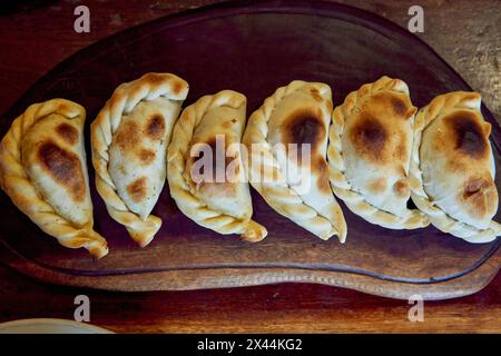 empanadas salteñas su una tavola di legno, ripiena di carne di manzo o di lama, cipolla, patate, peperoncino e spezie. vista dall'alto Foto Stock