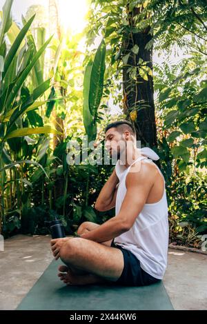 Vista laterale dell'uomo stanco che pulisce il sudore con un asciugamano dopo una sessione di yoga presso il centro benessere Foto Stock