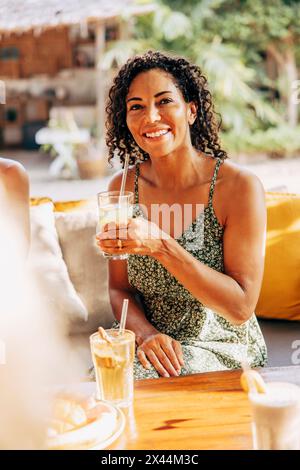 Ritratto di una donna matura sorridente che tiene in mano un bicchiere di succo mentre si siede al centro benessere Foto Stock
