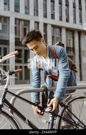 Uomo d'affari che chiude la bicicletta al parcheggio della città Foto Stock