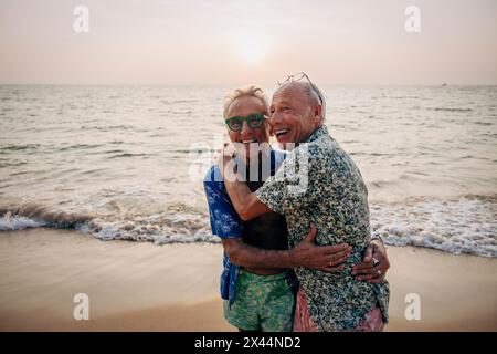 Allegra coppia gay senior che si abbracciano a vicenda in vacanza in spiaggia Foto Stock