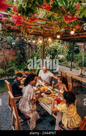 Famiglia felice che mangia da mangiare seduti al tavolo da pranzo del resort in vacanza Foto Stock