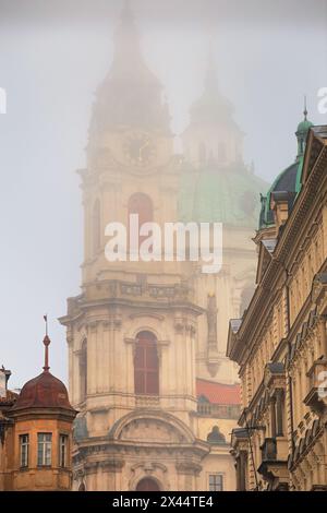 Paesaggio urbano in una mattinata nebbiosa - vista della Chiesa di San Nicola nel quartiere storico di Mala strana a Praga, Repubblica Ceca Foto Stock