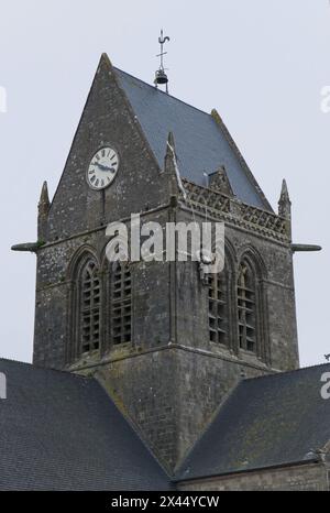 Sainte-Mere-Eglise, Francia - 19 aprile 2024: Chiesa di Sainte-Mere-Eglise. Gente che cammina a Sainte-Mere-Eglise. Strade ed edifici. Uno stile di vita nel nostro Foto Stock