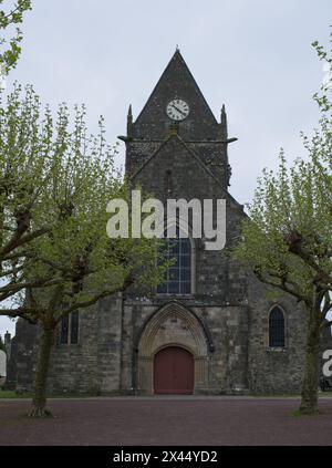 Sainte-Mere-Eglise, Francia - 19 aprile 2024: Chiesa di Sainte-Mere-Eglise. Gente che cammina a Sainte-Mere-Eglise. Strade ed edifici. Uno stile di vita nel nostro Foto Stock