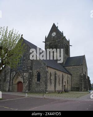 Sainte-Mere-Eglise, Francia - 19 aprile 2024: Chiesa di Sainte-Mere-Eglise. Gente che cammina a Sainte-Mere-Eglise. Strade ed edifici. Uno stile di vita nel nostro Foto Stock