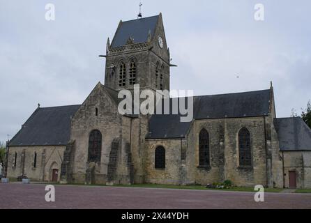 Sainte-Mere-Eglise, Francia - 19 aprile 2024: Chiesa di Sainte-Mere-Eglise. Gente che cammina a Sainte-Mere-Eglise. Strade ed edifici. Uno stile di vita nel nostro Foto Stock