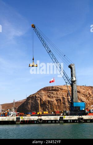 Gru mobile con spanditore per il sollevamento di container in porto, El Morro Headland in background, Arica, Cile Foto Stock