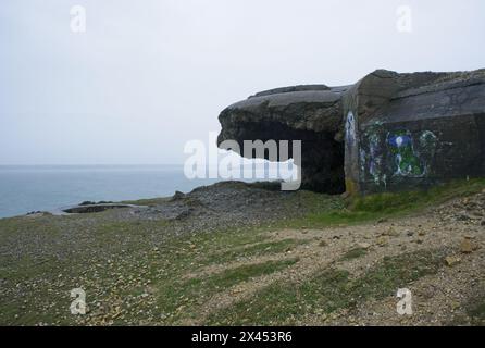 Vista della costa dall'esterno di un bunker tedesco bombardato della seconda guerra mondiale su Anse de Pen Hat, Bretagna. Faro. Nuvoloso giorno primaverile. Messa a fuoco selettiva Foto Stock