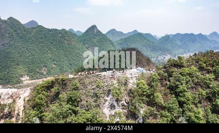 AnShun. 29 aprile 2024. Una foto aerea scattata il 29 aprile 2024 mostra muli che trasportano materiali da costruzione sulle montagne di Zhenning Buyi e della contea autonoma di Miao, nella provincia di Guizhou, nel sud-ovest della Cina. La costruzione della sottostazione 500 kV Bahe di China Southern Power Grid è entrata di recente nella fase finale. Il completamento del progetto è previsto per la fine di giugno. Crediti: Tao Liang/Xinhua/Alamy Live News Foto Stock