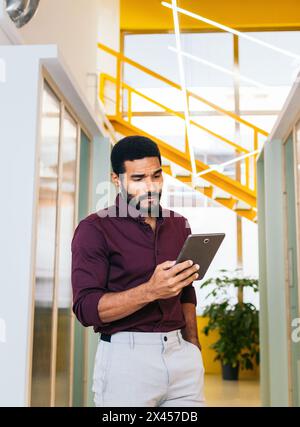 Bel latino in camicia che lavora con un tablet in un coworking Foto Stock