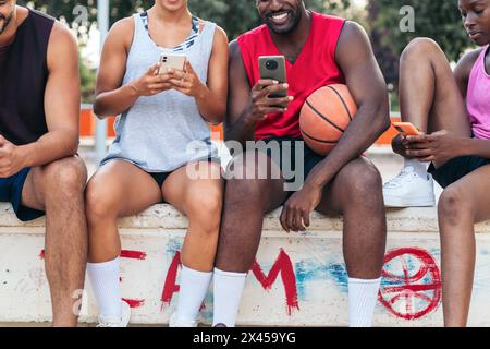 Gruppo di amici multirazziali che usano lo smartphone dopo una partita di basket Foto Stock