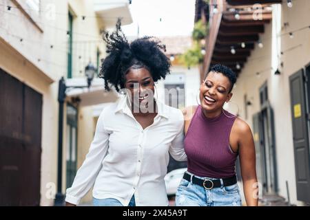 Eleganti amiche nere che si divertono e ridono molto camminando per strada Foto Stock