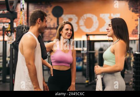 amici che parlano e si divertono in palestra mentre riposano Foto Stock