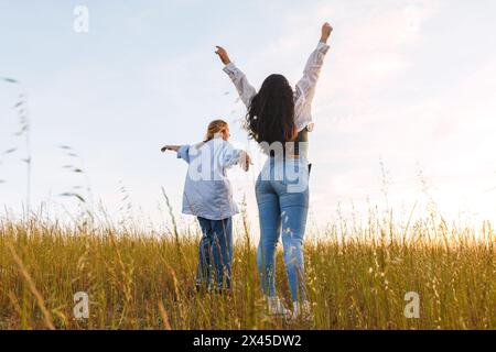 due amici donne che si divertano in un campo al tramonto Foto Stock