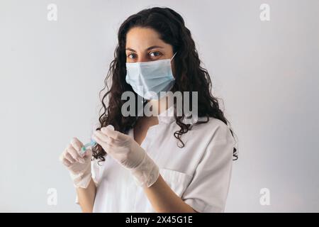 ritratto dell'infermiere con maschera che inietta il siero in una siringa Foto Stock