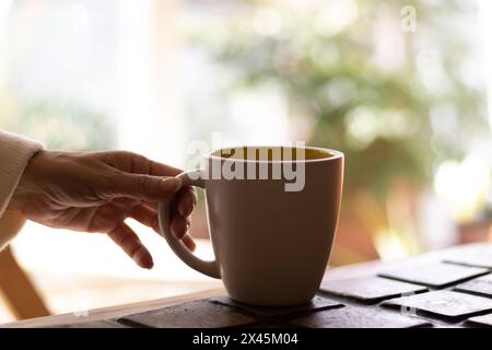 Mano di una donna matura che tiene una tazza di caffè. Foto Stock