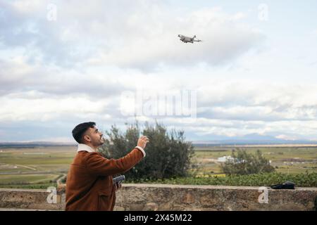 Giovane uomo che usa un drone per registrare e fotografare il paesaggio. Tiene il controller in una mano e con l'altra prenderà il drone Foto Stock