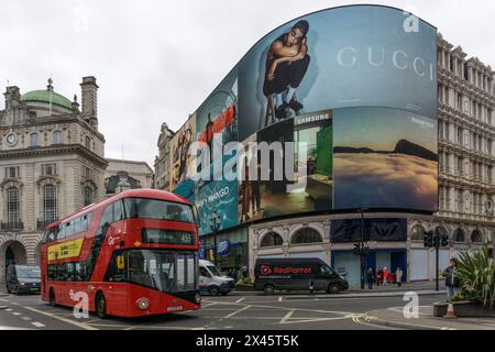 L'autobus rosso di Londra passa davanti a giganteschi video pubblicitari al Piccadilly Circus. Foto Stock